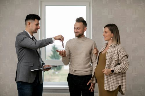 Drie mensen sluiten een deal waarbij een sleutel wordt overhandigd, symbool voor de groeiende toegankelijkheid van vastgoedinvesteringen.