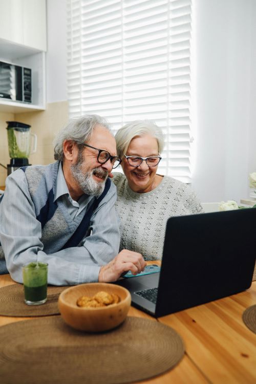 Twee gepensioneerde mensen achter een laptop die financiële plannen bespreken.