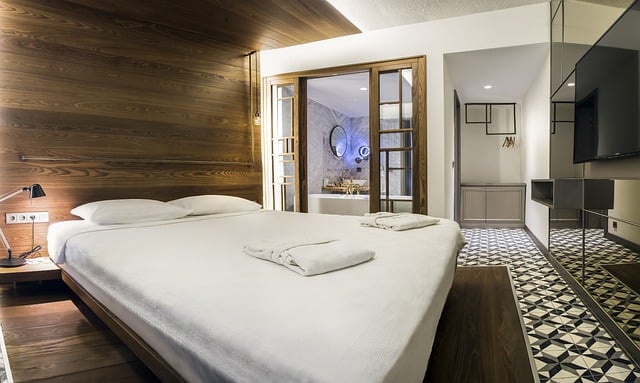 Een moderne hotelkamer met een groot bed, houten wandpanelen, een televisie en een luxe badkamer.