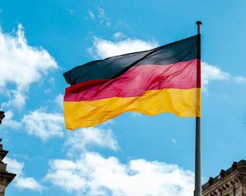 De Duitse vlag wappert tegen een blauwe hemel, symboliserend de economische kracht van Duitsland.